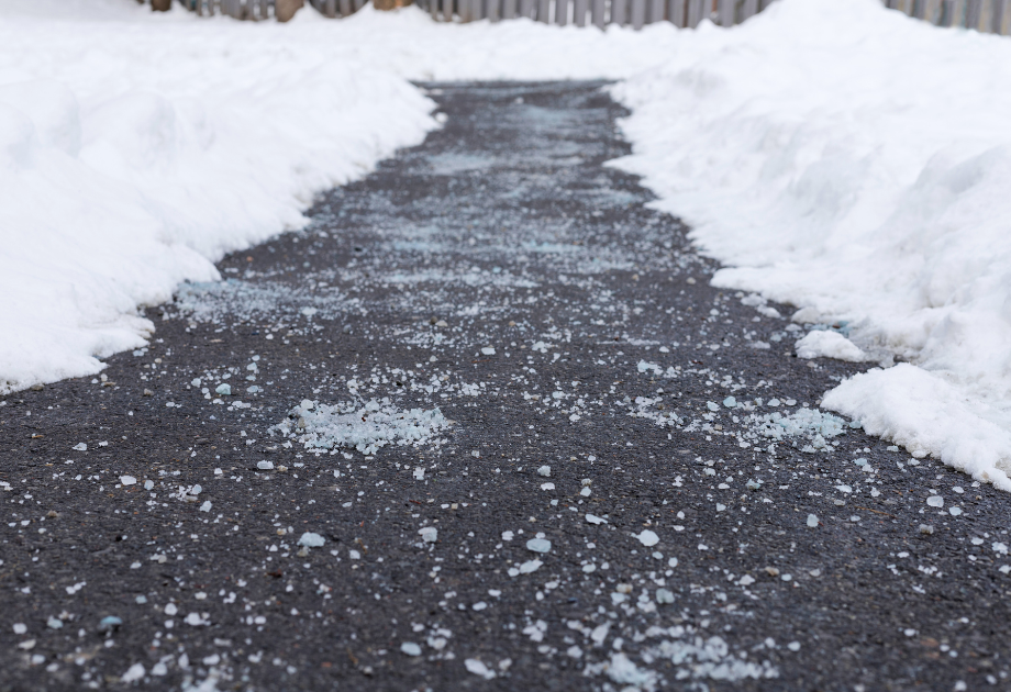 an asphalt path that has been shoveled of snow and a layer of salt deicer
