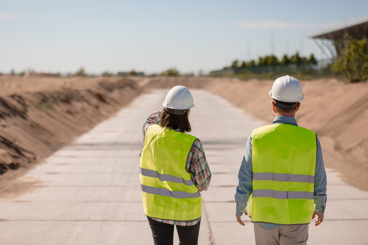 two people looking into the distance in yellow vests and construction hats
